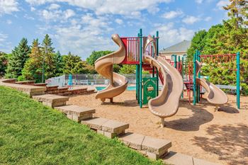 a playground with two slides and a grassy slope
